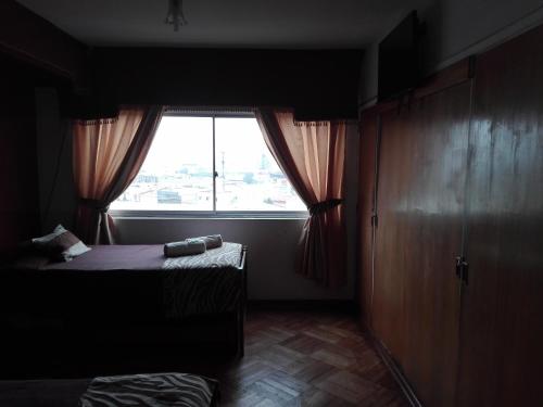 a dark room with a bed and a window at Hostal Tunquelen in Valparaíso