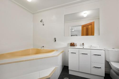 a bathroom with a sink and a tub and a toilet at Quest Trinity House in Hobart