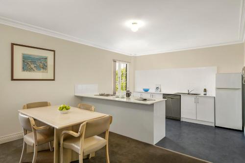 a kitchen with a table, chairs and a refrigerator at Quest Trinity House in Hobart