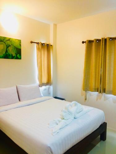 a bedroom with a bed with white sheets and yellow curtains at DE ROSE Hotel Chiang Mai in Chiang Mai