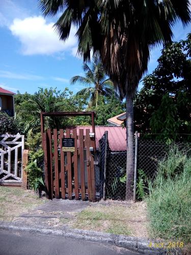 a gate in front of a house with a palm tree at La Villa Jasmin in Les Anses-dʼArlets