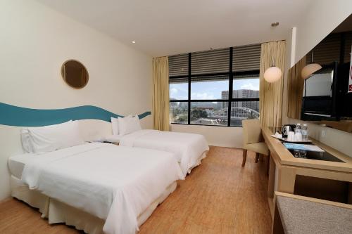 Cette chambre comprend deux lits et une télévision. dans l'établissement Oceania Hotel, à Kota Kinabalu