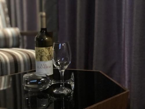 a bottle of wine and a wine glass on a table at Best Louis Hamilton Hotel Changwon in Changwon