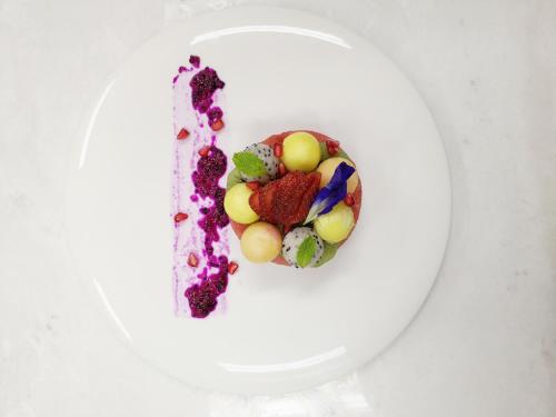 a white plate with a dessert with fruit on it at The Inside House in Chiang Mai