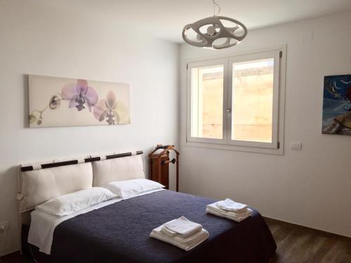 a bedroom with a bed with a blue blanket and a window at Modern Flat Lecce ++ in Lecce