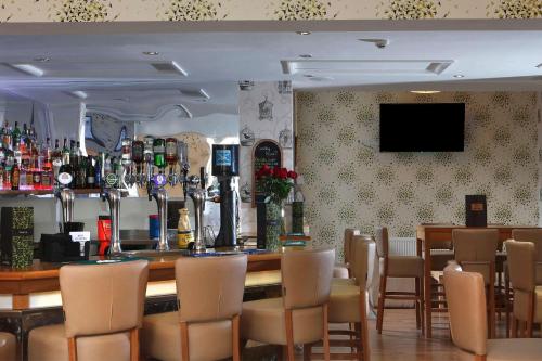 a restaurant with a bar with chairs and a television at Deincourt Hotel in Newark upon Trent