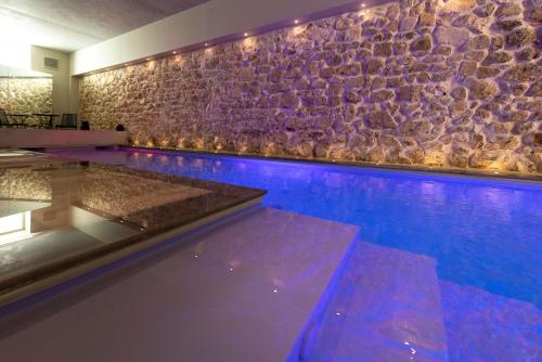 a swimming pool with a stone wall and purple lighting at Best Western Plus Hôtel La Joliette in Marseille