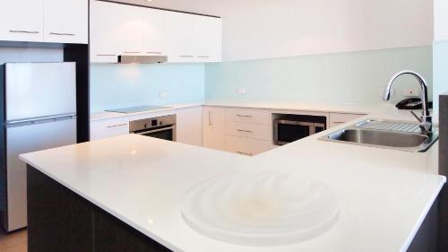 a kitchen with a white counter and a sink at Oaks Townsville Gateway Suites in Townsville