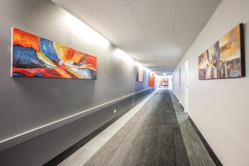 a corridor in an office building with paintings on the walls at Nightcap at Coolaroo Hotel in Coolaroo