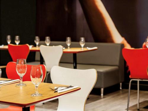 a restaurant with tables and chairs with wine glasses on them at ibis Issy les Moulineaux "Val de Seine" in Issy-les-Moulineaux