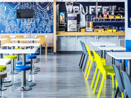 a restaurant with yellow chairs and tables and a counter at Ibis Budget Fréjus St Raphaël centre in Fréjus