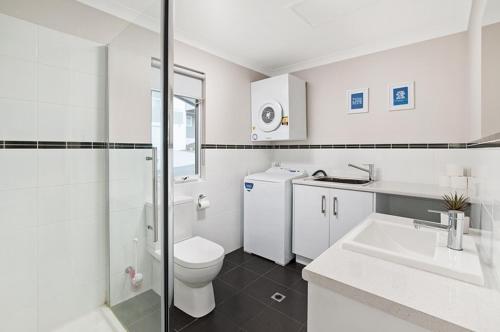 a white bathroom with a toilet and a sink at Forest View Villa in Dunsborough