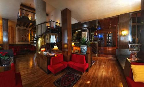 a living room with red chairs and a staircase at Hotel Paladin in San Martino di Castrozza