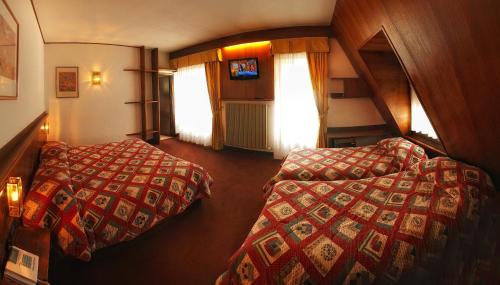 a room with two beds and a staircase with windows at Hotel Paladin in San Martino di Castrozza