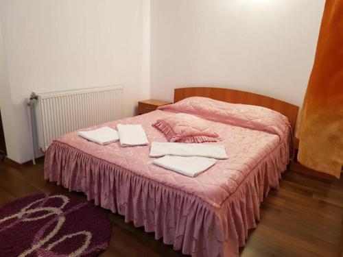 ein Bett mit einer rosa Decke und Handtüchern darauf in der Unterkunft Hotel Magnolia in Aiud