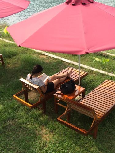 a woman laying on a chair under a pink umbrella at Carambola Bungalow in Phong Nha