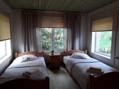 two beds in a room with two windows at Brīvdienu māja Melderi in Ape