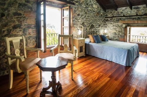 1 dormitorio con 1 cama y sillas en una pared de piedra en La Vega de Pendueles, en Pendueles