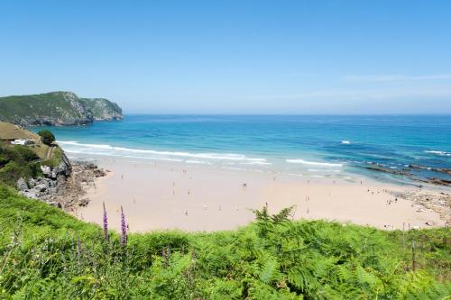 a beach with people on the sand and the ocean at La Vega de Pendueles in Pendueles