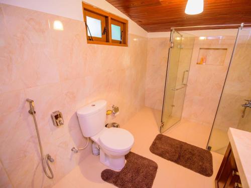 a bathroom with a toilet and a glass shower at The Berrycove Bungalow in Kurunegala