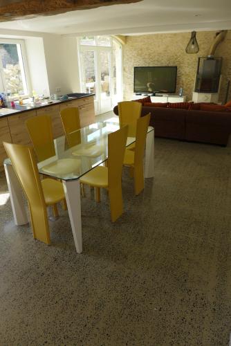 a dining room with a table and yellow chairs at Le Semoir in Bény-sur-Mer