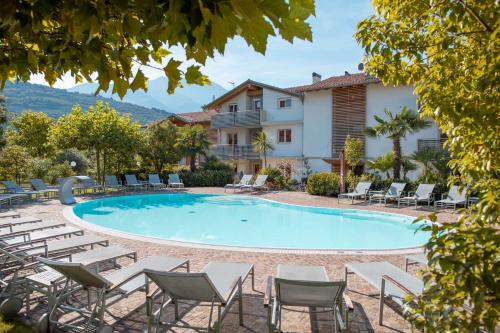 a large swimming pool with chairs and a building at 4 Limoni Apartment Resort in Riva del Garda