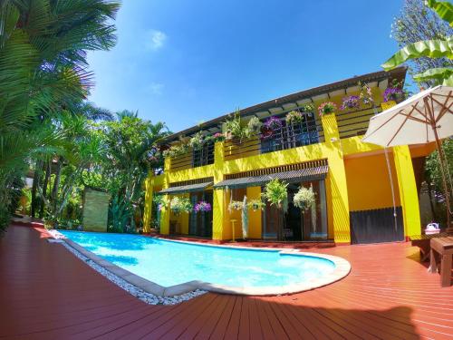 a swimming pool in front of a yellow building at Lamduan Boutique Homestay in Chiang Mai