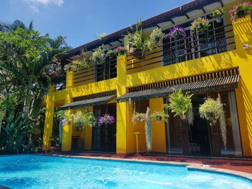 a yellow building with a swimming pool in front of it at Lamduan Boutique Homestay in Chiang Mai