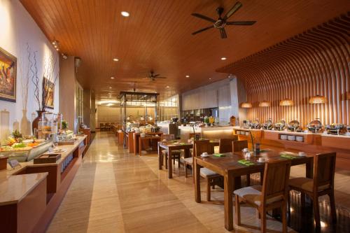 restauracja z drewnianymi sufitami i stołami oraz kuchnią w obiekcie Hotel Santika Banyuwangi w mieście Banyuwangi