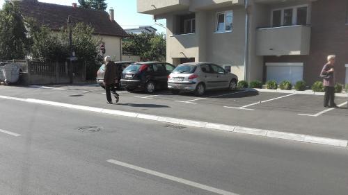 Um homem a andar pela rua num parque de estacionamento. em Olivia em Jagodina
