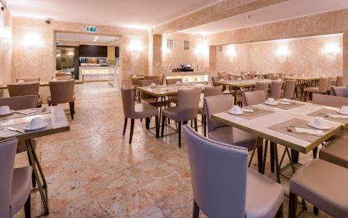 a restaurant with tables and chairs and a kitchen at BW Premier Collection CHC Continental in Venice