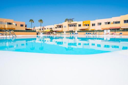 een leeg zwembad met palmbomen en gebouwen bij Lur de la playa in Corralejo