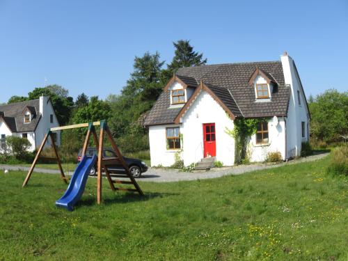 a house with a playground in front of a house at Heatherhill Farm Cottage in Letterfrack beside Connemara National Park in Letterfrack
