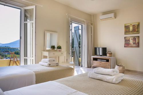 een slaapkamer met 2 bedden, een televisie en een balkon bij Villa Isalos in Fiskardho