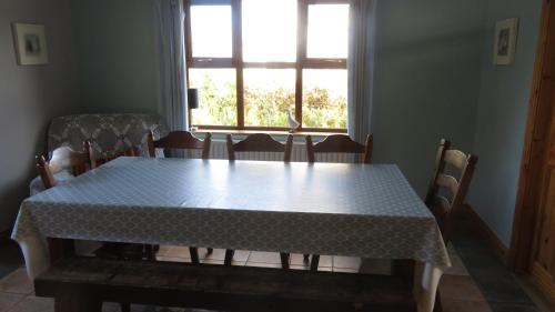 a table and chairs with a table and a window at Heatherhill Farm Cottage in Letterfrack beside Connemara National Park in Letterfrack