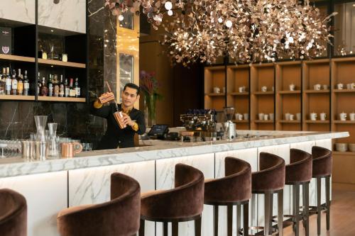 a man standing behind a bar with chairs at Banyan Tree Kuala Lumpur in Kuala Lumpur