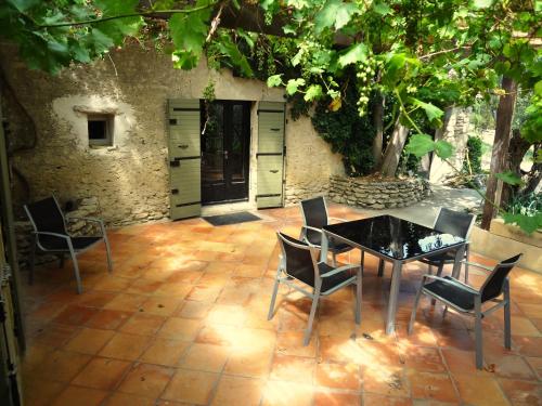 un patio con tavolo e sedie di fronte a un edificio di Les Olives a Uzès