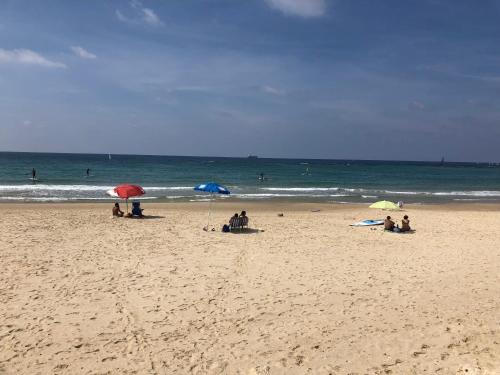 a group of people sitting on a beach with umbrellas at Suite Caesar - Neot Golf in Caesarea