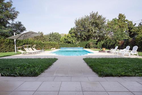 a swimming pool with lounge chairs and an umbrella at Villa Casetti B&B in Fontanelice