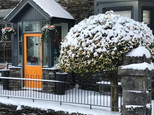 a house with a snow covered tree in front of it at Holly Lodge Guest House with FREE off site health club in Windermere