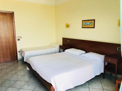 una habitación de hotel con 2 camas y una puerta en Hotel Elisabetta, en Castellammare di Stabia