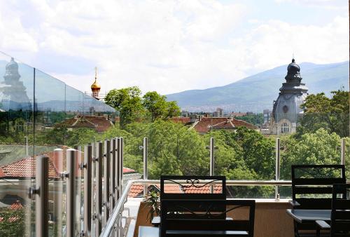 a balcony with chairs and a view of a city at Arena Di Serdica Hotel in Sofia