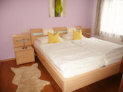 a bedroom with a large bed with yellow pillows at Ferienwohnungen Tweraser in Bad Birnbach