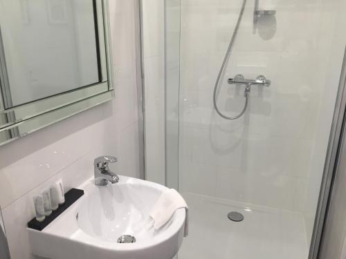 a white bathroom with a sink and a shower at Antwerp Town House Accommodations in Antwerp