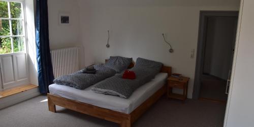 łóżko z szarymi poduszkami i czerwonym niedźwiedziem w obiekcie Ferienwohnung am Ostseebad w mieście Flensburg