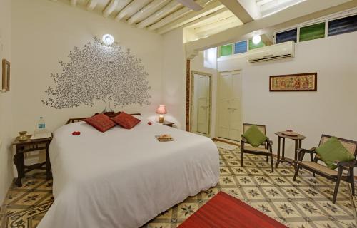 una camera da letto con un grande letto bianco e due sedie di French Haveli a Ahmedabad
