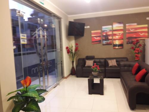 a living room with couches and a tv at Gavina Inn Hotel in Tacna