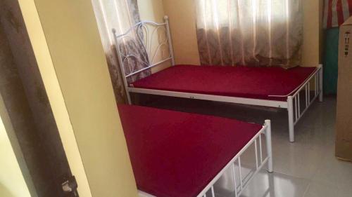 two beds in a room with red and white at Jireh’s Guests Home in Butuan