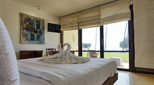 Un dormitorio con una cama blanca con cisnes. en Grand Beach, en Wadduwa