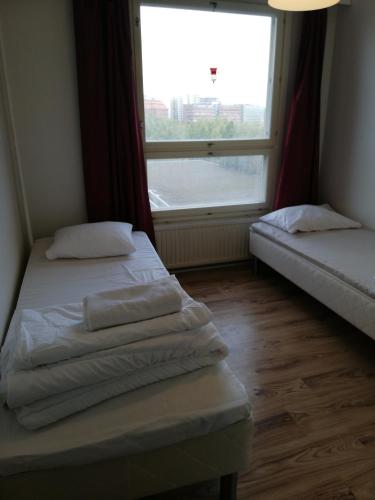 two beds in a room with a large window at apartment in great location in Helsinki